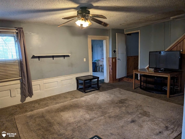 carpeted living room featuring ceiling fan and a textured ceiling