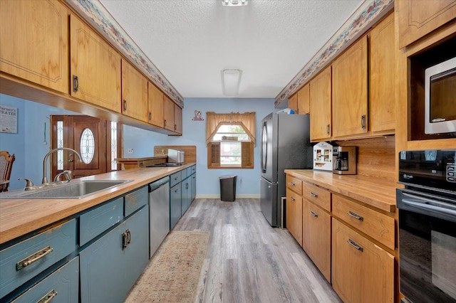 kitchen featuring a textured ceiling, stainless steel appliances, light hardwood / wood-style flooring, and sink