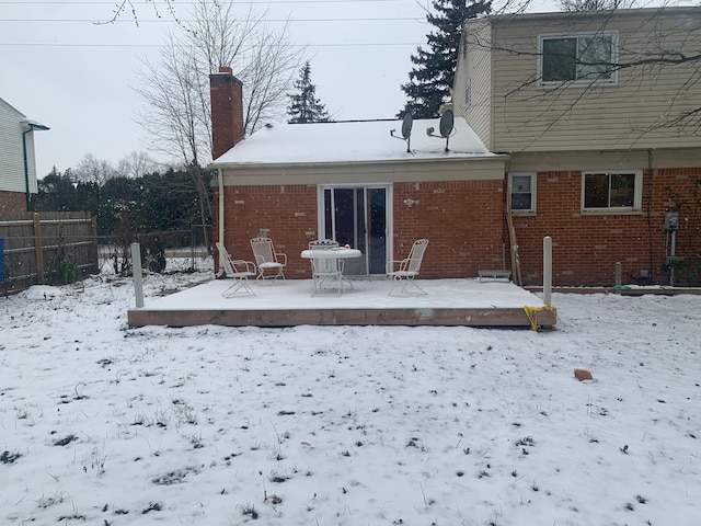 snow covered back of property with a deck