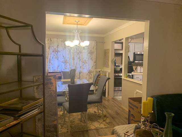 dining area featuring crown molding, wood-type flooring, and an inviting chandelier