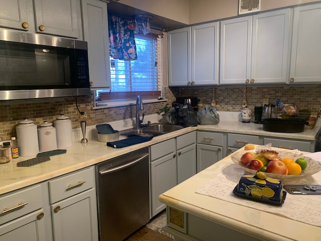 kitchen with gray cabinets, decorative backsplash, sink, and stainless steel appliances