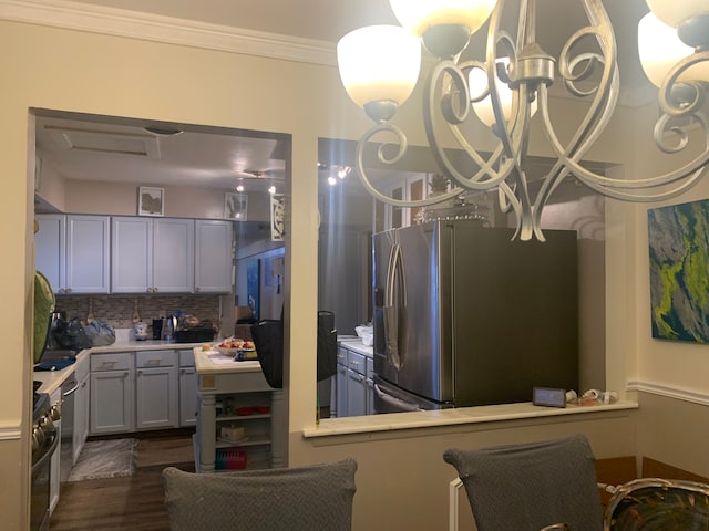 kitchen with dark hardwood / wood-style floors, stainless steel fridge, ornamental molding, tasteful backsplash, and a chandelier