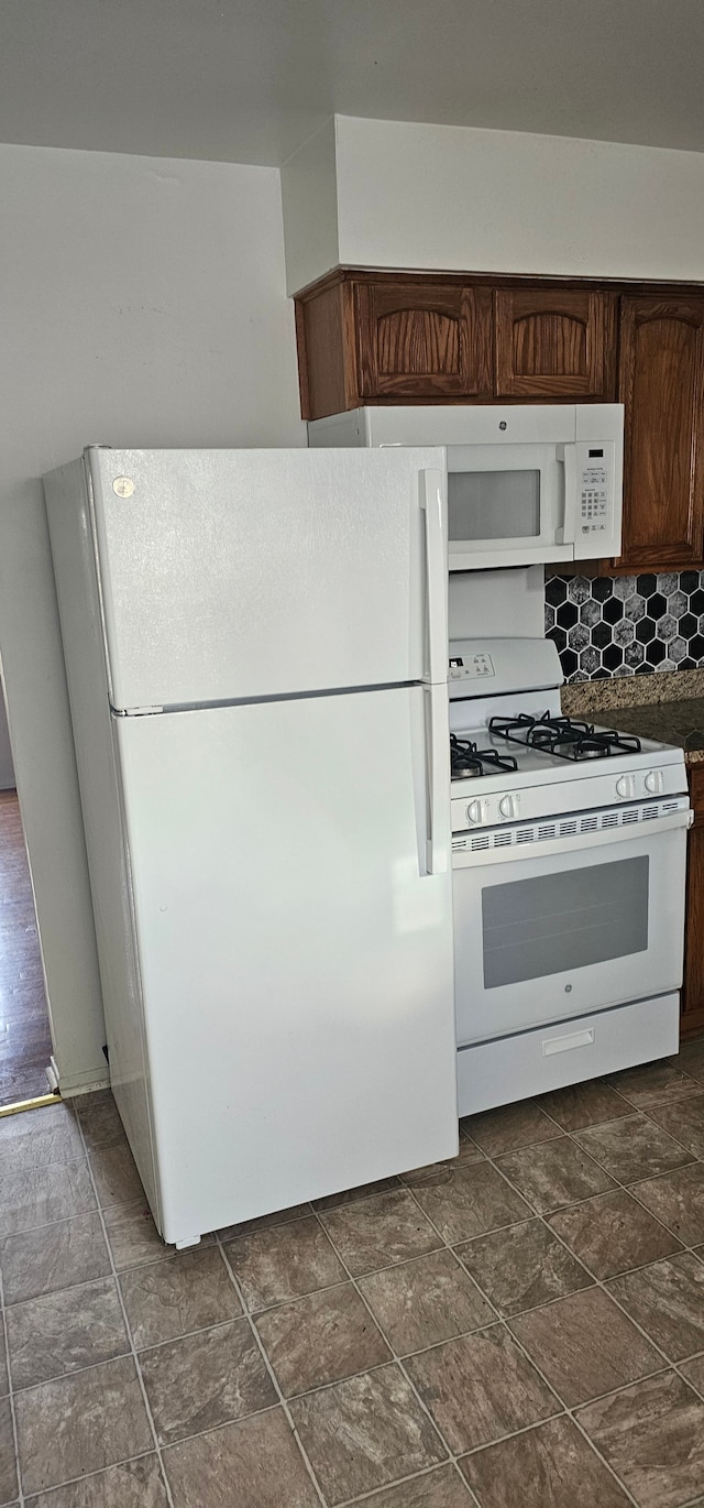 kitchen with backsplash, dark brown cabinets, and white appliances