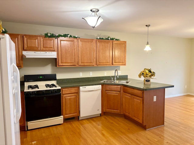 kitchen featuring sink, kitchen peninsula, pendant lighting, light hardwood / wood-style floors, and white appliances