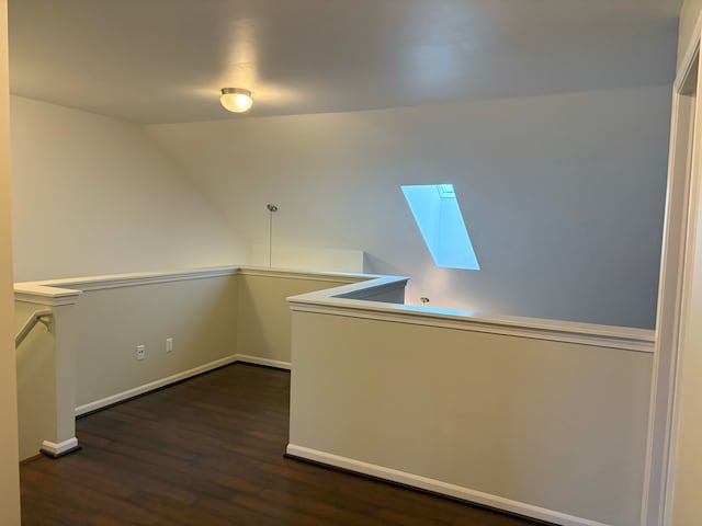 interior space with dark hardwood / wood-style floors and vaulted ceiling with skylight