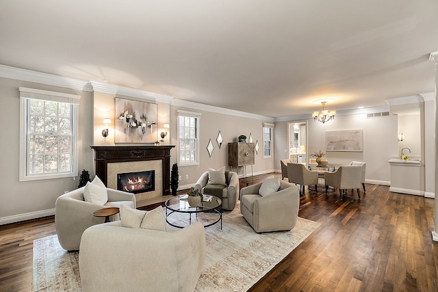 living room with a notable chandelier, wood-type flooring, ornamental molding, and a healthy amount of sunlight