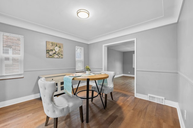 dining room with hardwood / wood-style floors and crown molding