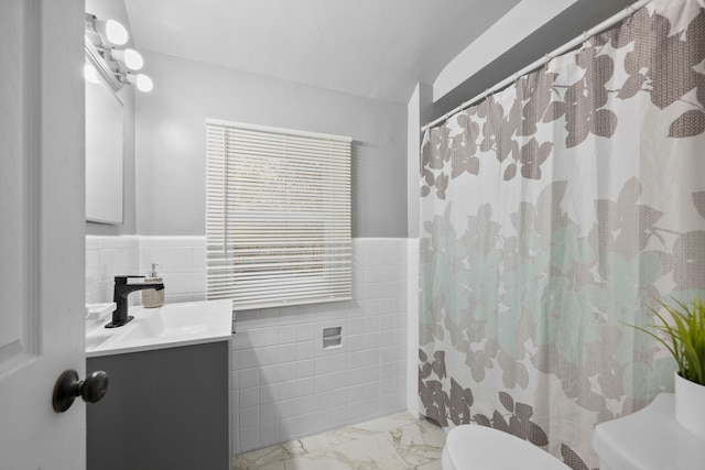 bathroom with vanity, toilet, and tile walls