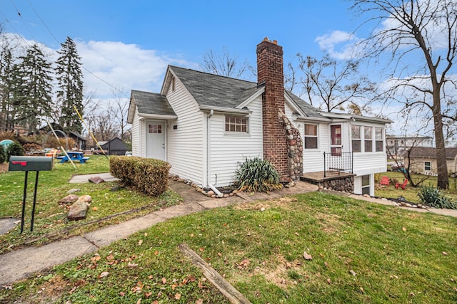 view of home's exterior with a sunroom and a lawn