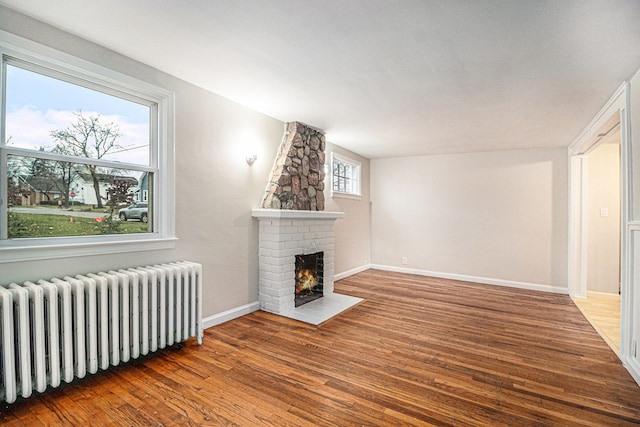 unfurnished living room featuring hardwood / wood-style flooring, a fireplace, and radiator