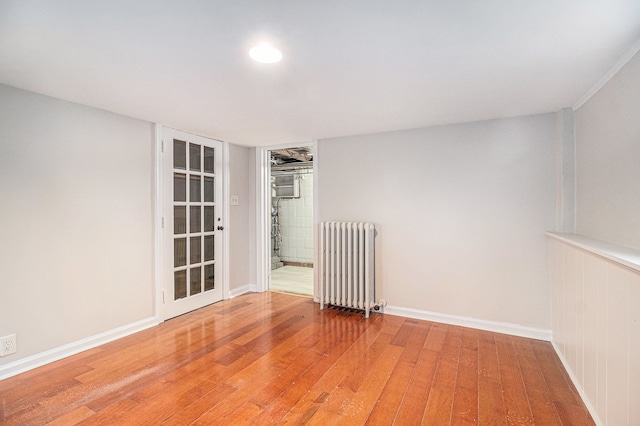 empty room with wood-type flooring and radiator