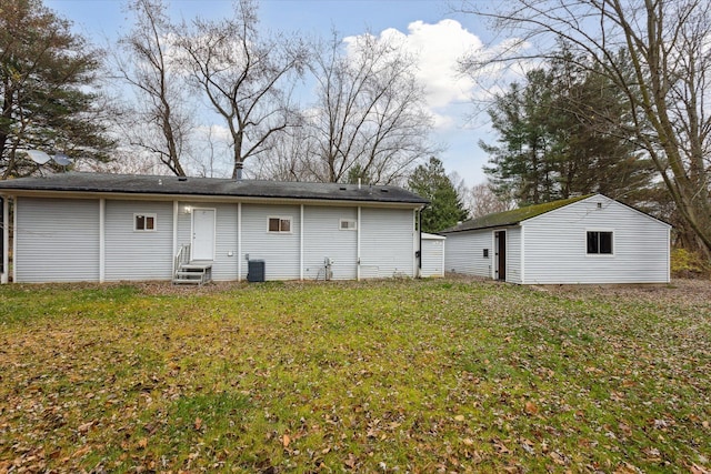 rear view of property featuring a lawn, an outdoor structure, and central AC unit