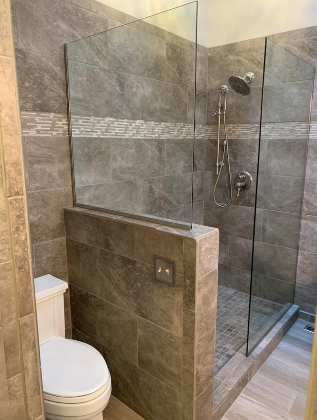 bathroom with tiled shower and toilet