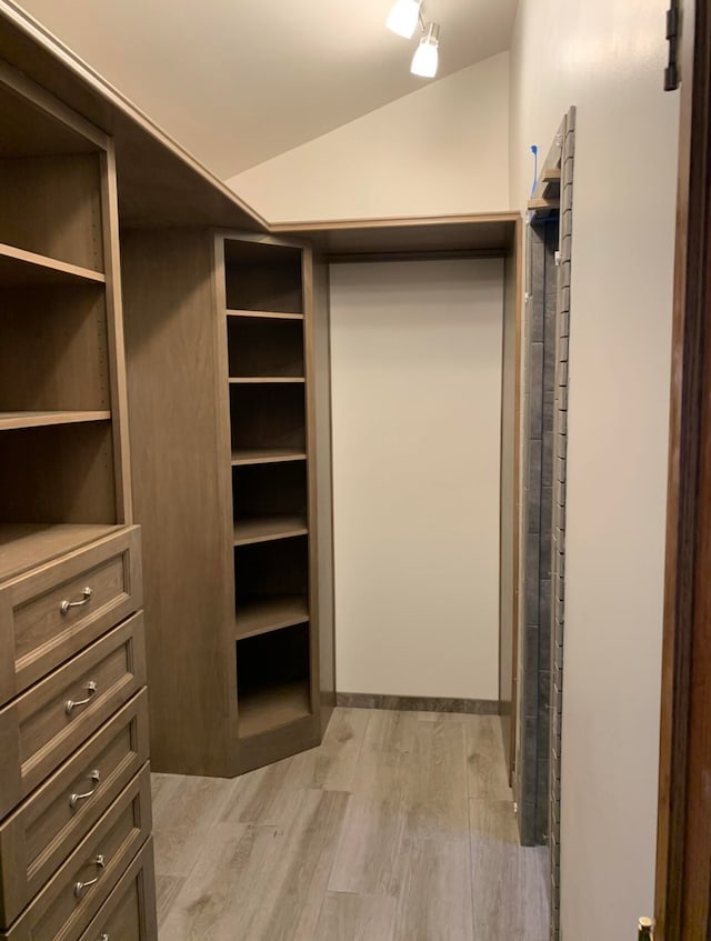 walk in closet with light wood-type flooring and lofted ceiling