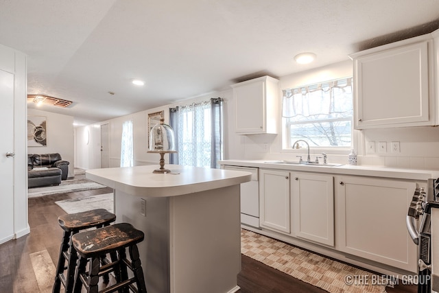 kitchen featuring a kitchen bar, dishwasher, a center island, dark hardwood / wood-style floors, and white cabinetry