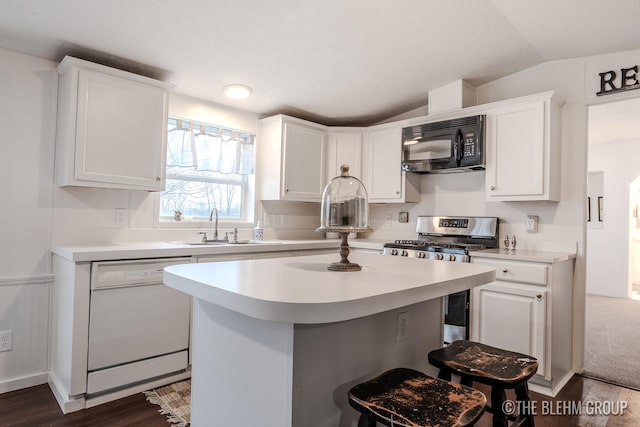 kitchen with dishwasher, sink, vaulted ceiling, stainless steel range oven, and white cabinetry