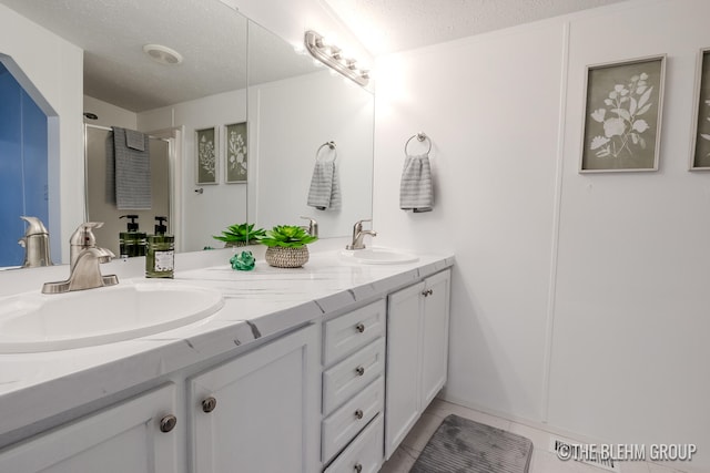 bathroom featuring tile patterned flooring, vanity, a textured ceiling, and walk in shower