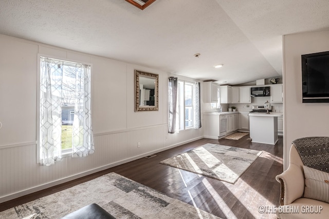 kitchen with white cabinets, dark hardwood / wood-style flooring, vaulted ceiling, and plenty of natural light