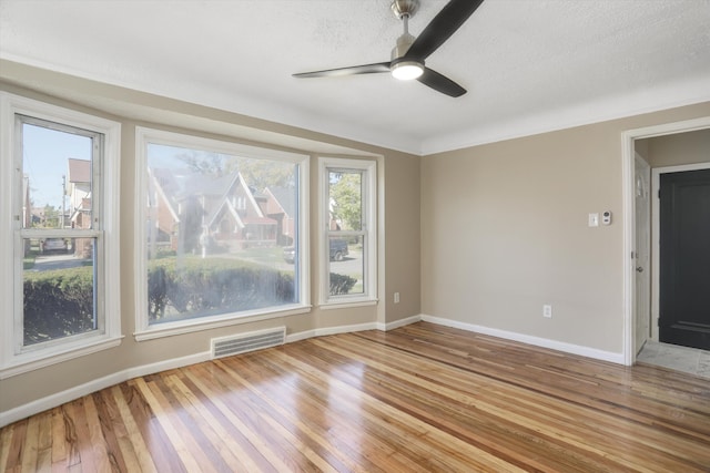 empty room featuring a textured ceiling, light hardwood / wood-style flooring, and ceiling fan