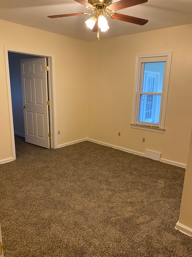 empty room featuring dark colored carpet and ceiling fan