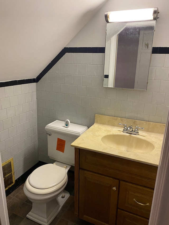 bathroom featuring vanity, toilet, lofted ceiling, and tile walls