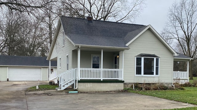 view of front of property featuring a garage, covered porch, an outbuilding, and central AC