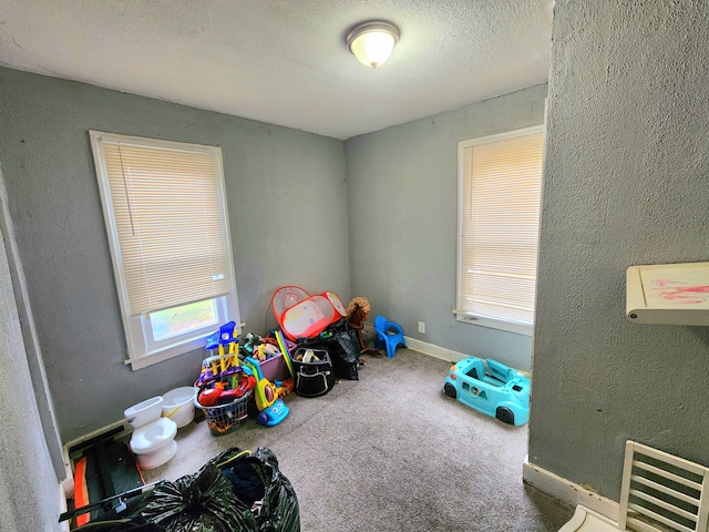 recreation room featuring carpet and a textured ceiling