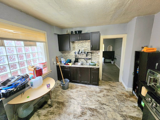 kitchen with decorative backsplash, dark brown cabinets, a textured ceiling, and sink