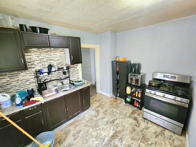 kitchen featuring backsplash, sink, stainless steel gas range, a textured ceiling, and dark brown cabinetry