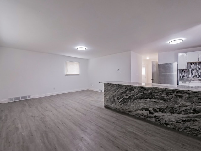 interior space with tasteful backsplash, stainless steel refrigerator, white cabinetry, and dark hardwood / wood-style flooring