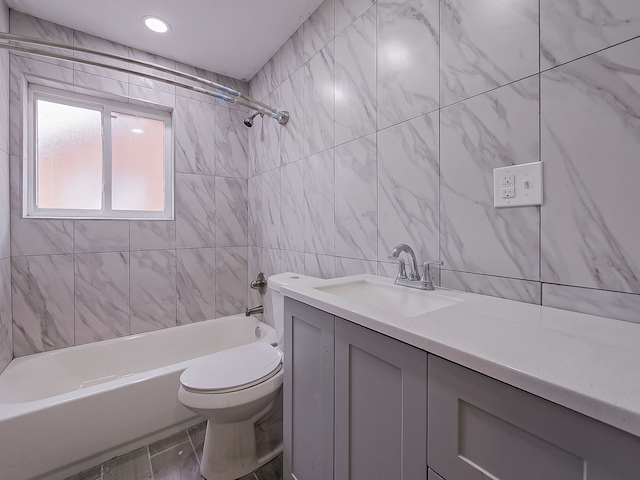 full bathroom featuring vanity, tiled shower / bath combo, tile walls, and toilet