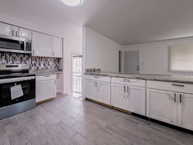 kitchen featuring white cabinets, light stone countertops, stainless steel appliances, and light hardwood / wood-style flooring