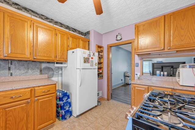 kitchen featuring ceiling fan, light tile patterned flooring, white appliances, and backsplash