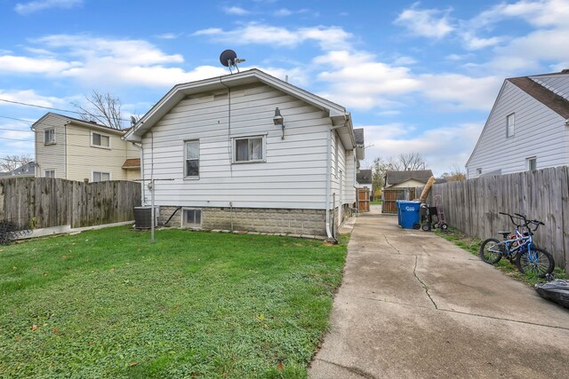back of house featuring a lawn and central air condition unit