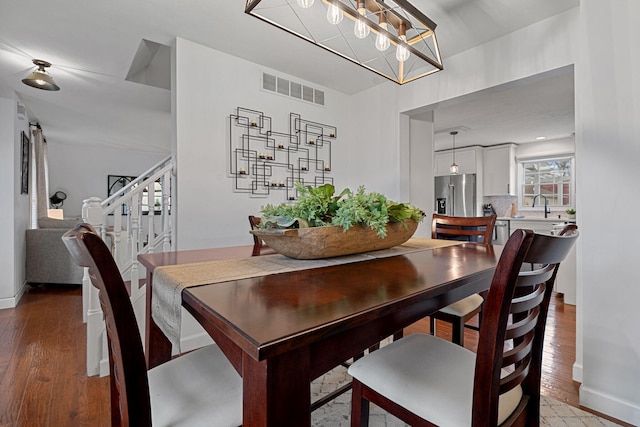 dining room featuring sink, a chandelier, and light wood-type flooring