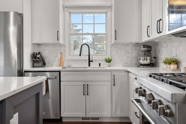 kitchen with white cabinets, backsplash, sink, and appliances with stainless steel finishes