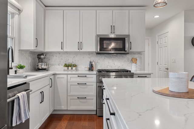 kitchen featuring dark hardwood / wood-style floors, light stone countertops, tasteful backsplash, white cabinetry, and stainless steel appliances