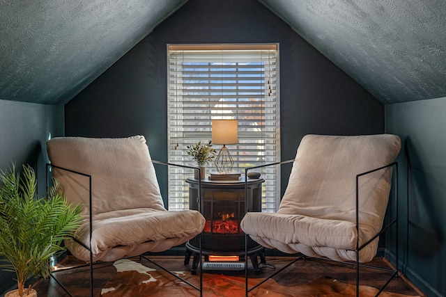 sitting room with a textured ceiling and vaulted ceiling