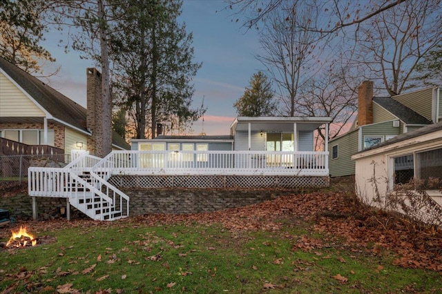 back of house at dusk with a wooden deck