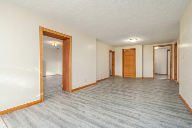 unfurnished room featuring light hardwood / wood-style floors and a textured ceiling