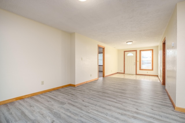 empty room featuring a textured ceiling and light hardwood / wood-style flooring