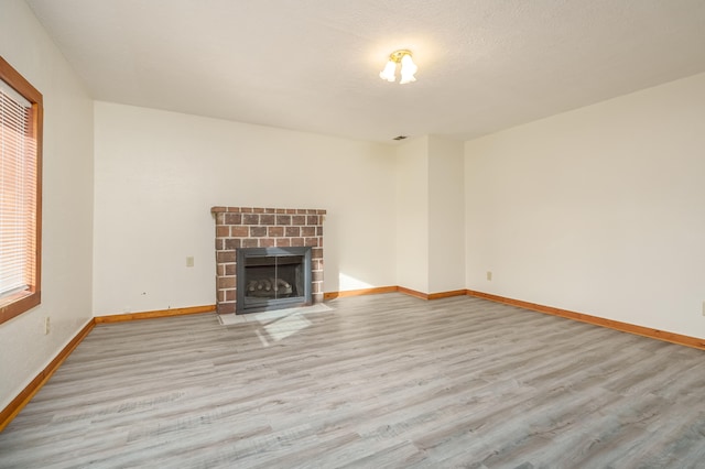 unfurnished living room with light hardwood / wood-style floors, a textured ceiling, and a wealth of natural light