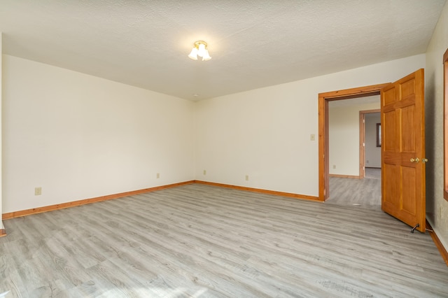 empty room featuring light wood-type flooring and a textured ceiling