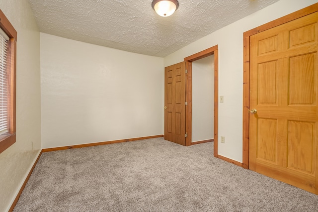 unfurnished bedroom with a textured ceiling and light carpet