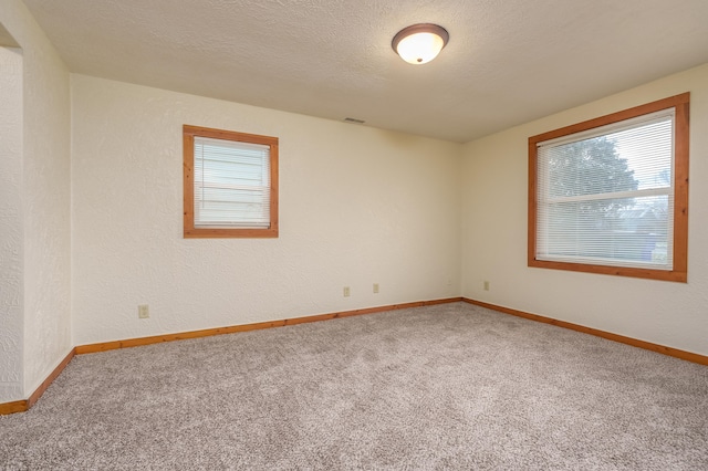 unfurnished room with a textured ceiling and carpet floors