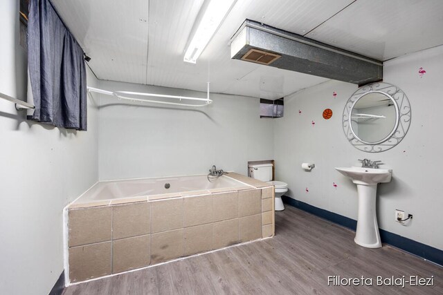 4481 Marshall Ave SE, Grand Rapids, MI 49508 - full bathroom with tiled tub, toilet, wood finished floors, and baseboards