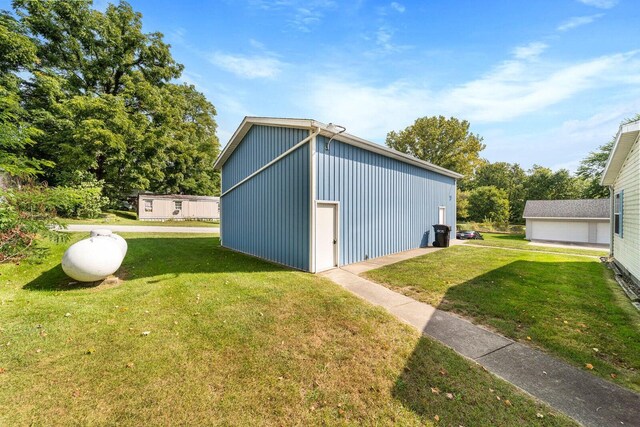 view of home's exterior featuring a lawn, a detached garage, and an outbuilding