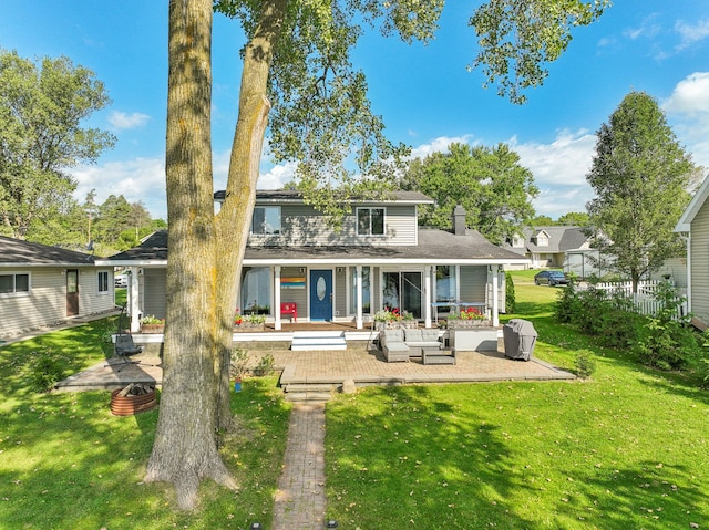 rear view of property featuring a patio area, a yard, and an outdoor hangout area