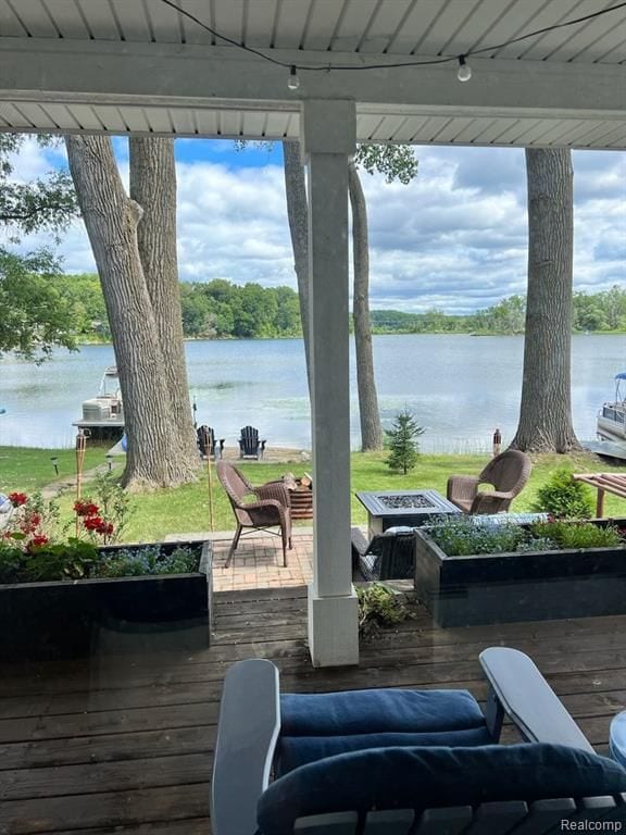 wooden terrace featuring a water view and an outdoor fire pit