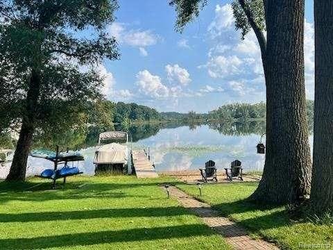 view of home's community with a yard, a water view, and a boat dock